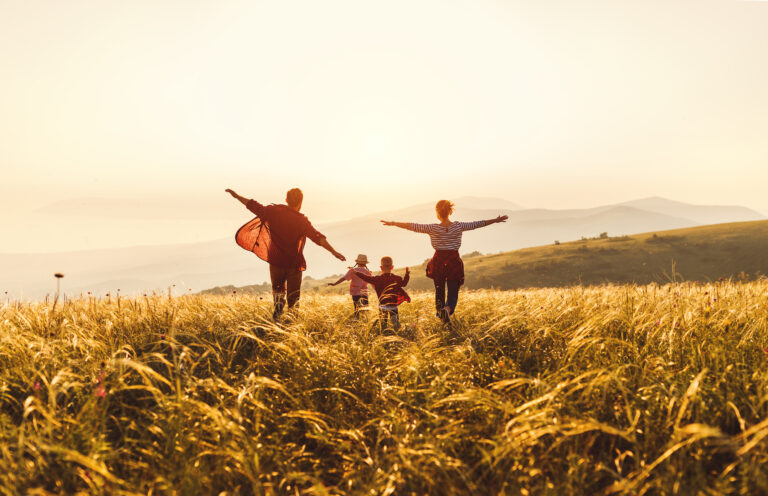 Happy family: mother, father, children son and daughter runing and jumping on sunset